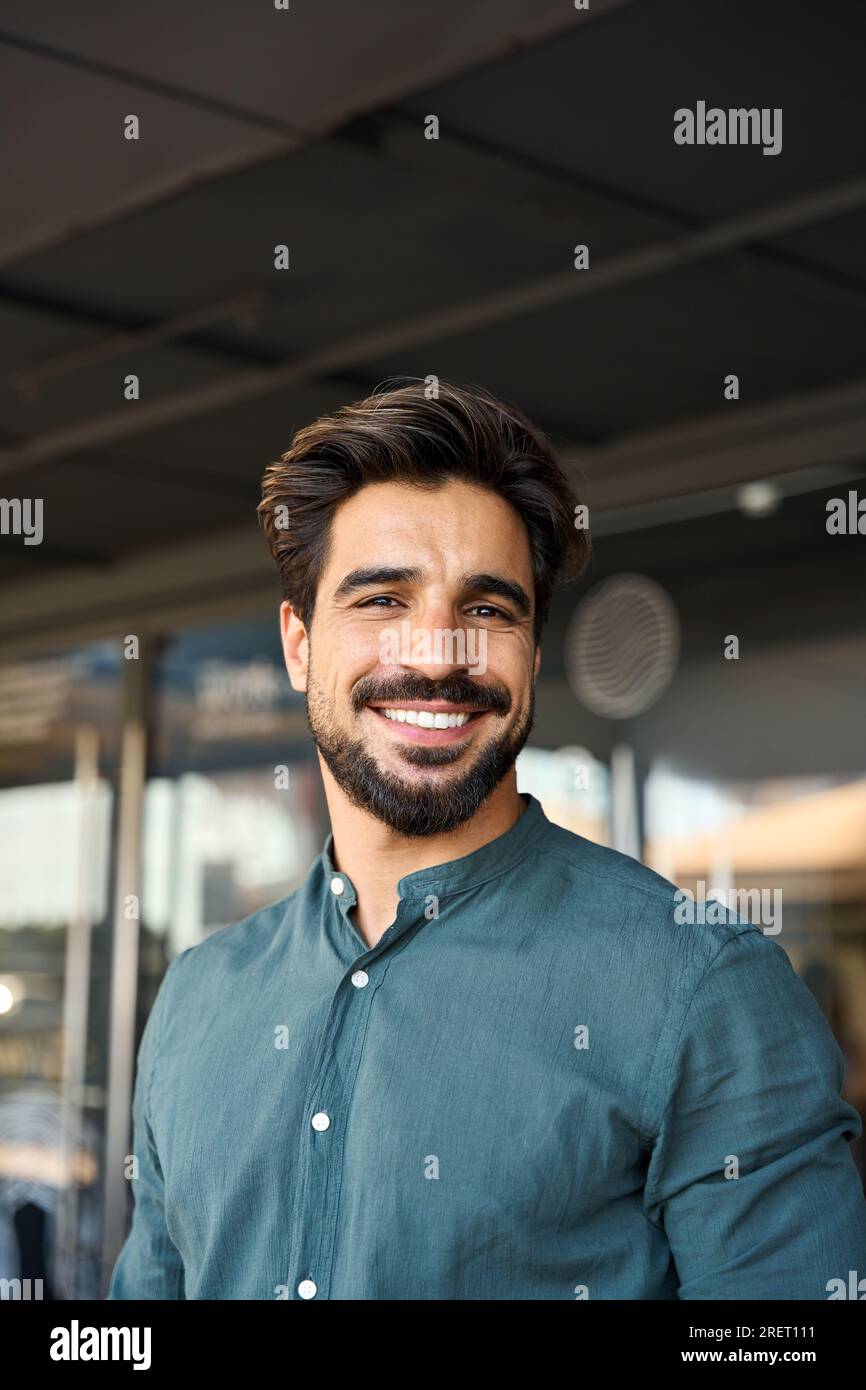 Felice giovane uomo d'affari latino che guarda la macchina fotografica e il ritratto verticale. Foto Stock