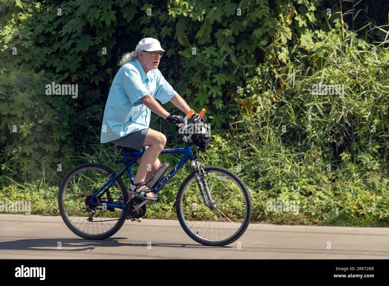 THAILANDIA, FEB 26 2023, un anziano cavalca una bicicletta nella campagna tailandese Foto Stock