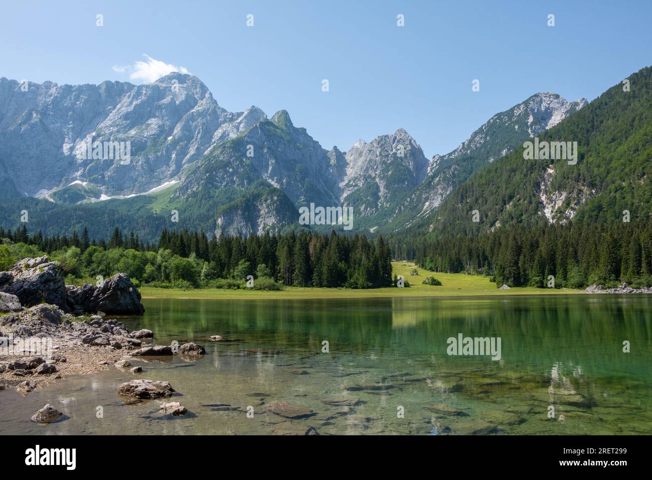 Vista delle acque turchesi del Lago Die Fusine superiore nelle Alpi Giulie dell'Italia nord-orientale con la spettacolare parete rocciosa del Monte Mangart Foto Stock