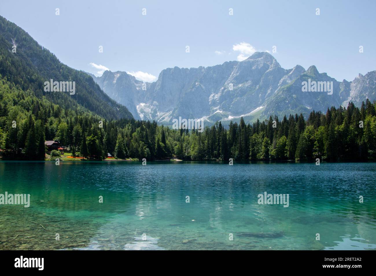 Vista del Lago inferiore Die Fusine nelle Alpi Giulie dell'Italia nord-orientale con la spettacolare parete rocciosa del Monte Mangart sullo sfondo Foto Stock