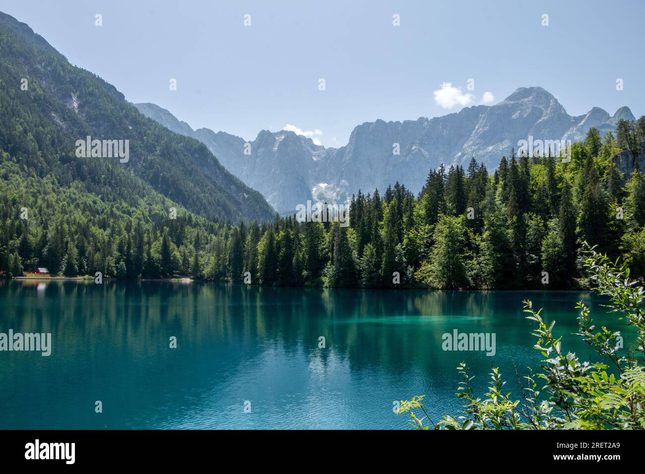 Vista del Lago inferiore Die Fusine nelle Alpi Giulie dell'Italia nord-orientale con la spettacolare parete rocciosa del Monte Mangart sullo sfondo Foto Stock