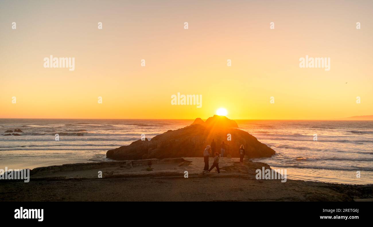 Gruppo in spiaggia durante un tramonto vivido. Foto Stock