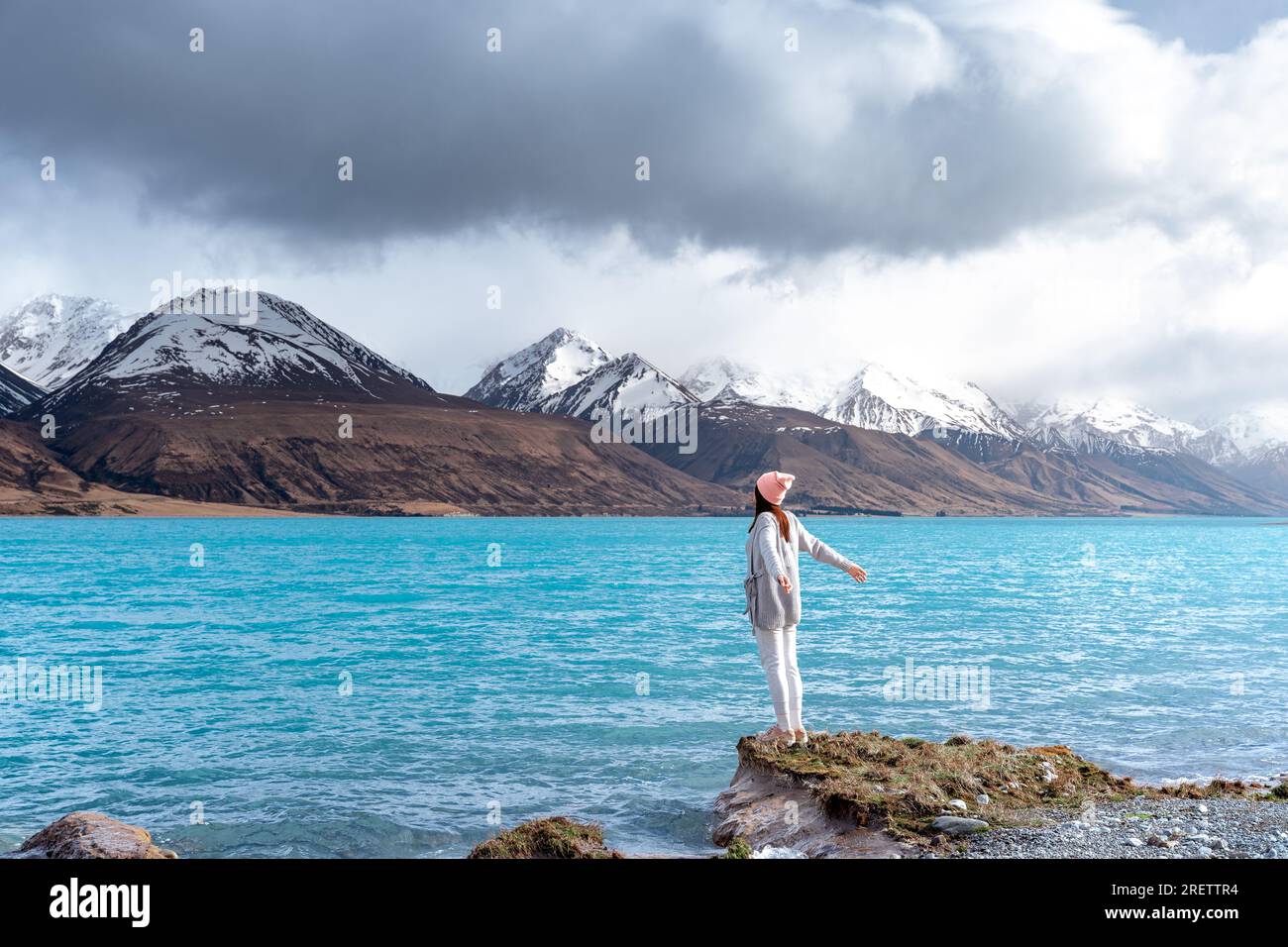 Modella asiatica femminile goditi la splendida vista panoramica dell'alba sulla sponda orientale del lago Pukaki, con la loro affascinante tonalità turchese. Foto Stock