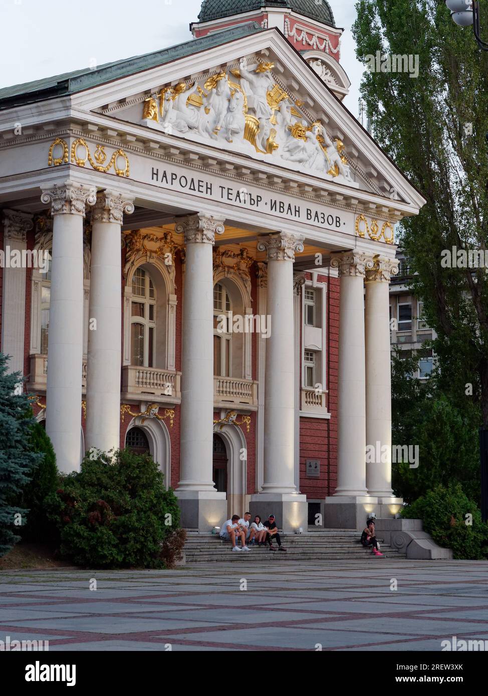 La gente si siede sui gradini del Teatro Nazionale Ivan Vazov ambientato nell'area dei Giardini della città, Sofia, Bulgaria. 29 luglio 2023 Foto Stock