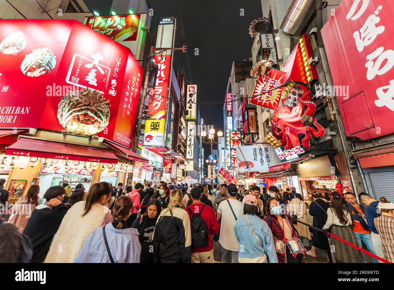Vita notturna a Dotonbori, Osaka, vista dai popolari ristoranti Takoyaki Juhachiban e Konamon Museum lungo la trafficata e vivace strada illuminata al neon Foto Stock