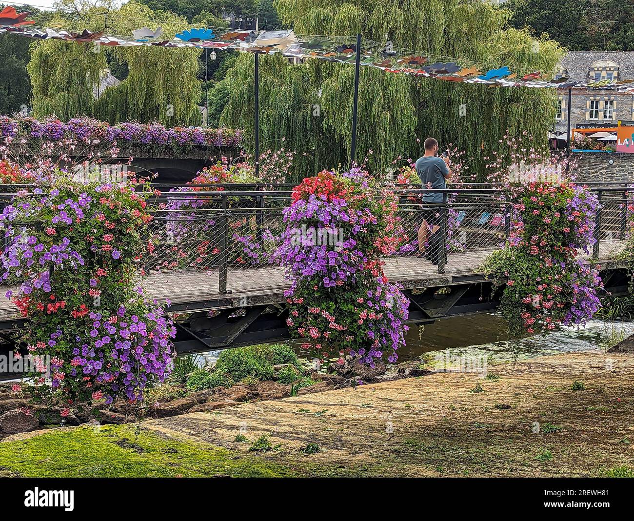 C) Denis TRASFI / MAXPPP - Francia, Bretagne, Morbihan, Maison Yves Rocher à Gacilly le 20 juillet 2023 - Pont piéton fleuri au-dessus de la rivière L. Foto Stock