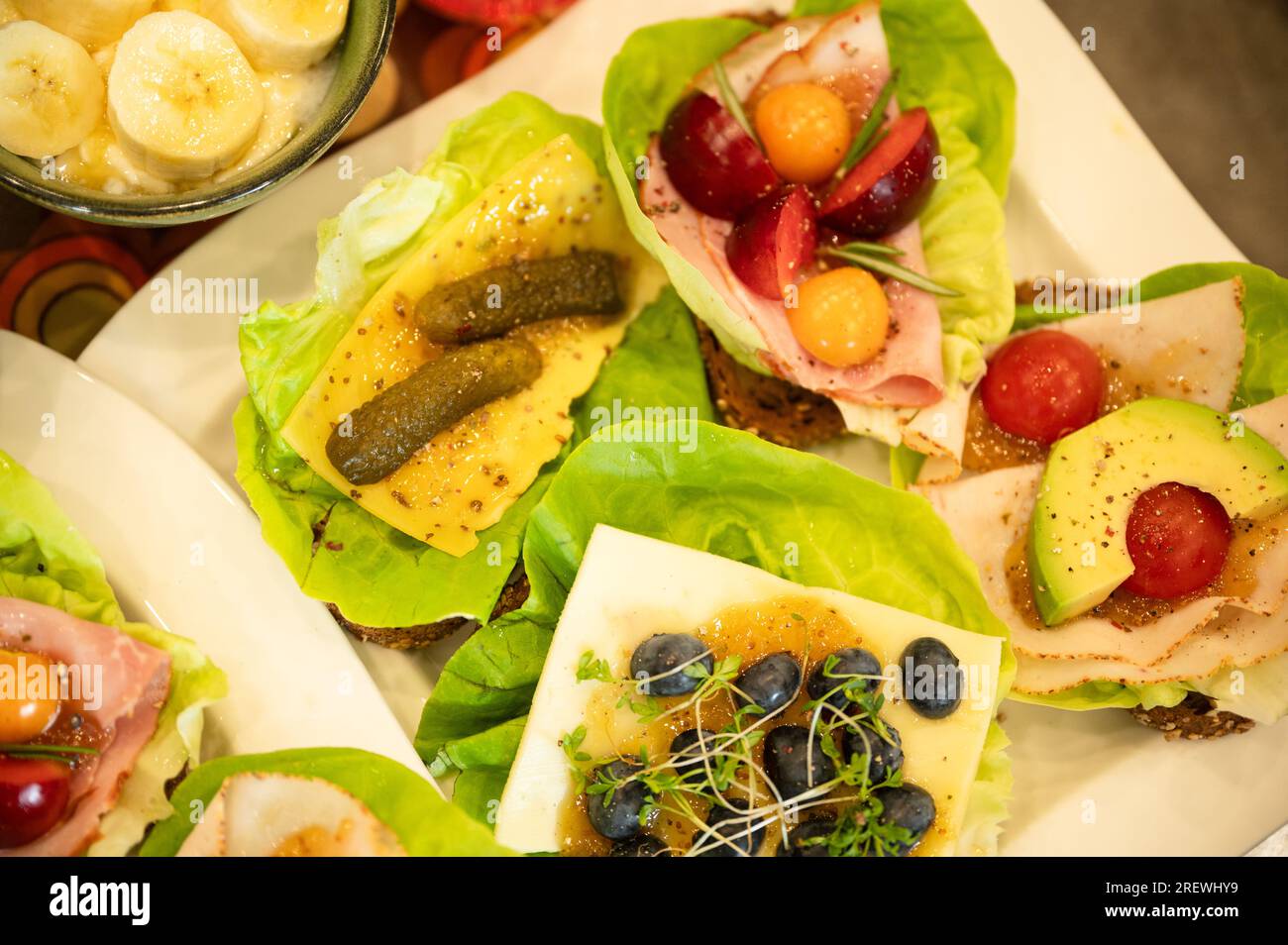 Panini sani e colorati con insalata, frutti di bosco, marmellata, formaggio e affettati Foto Stock
