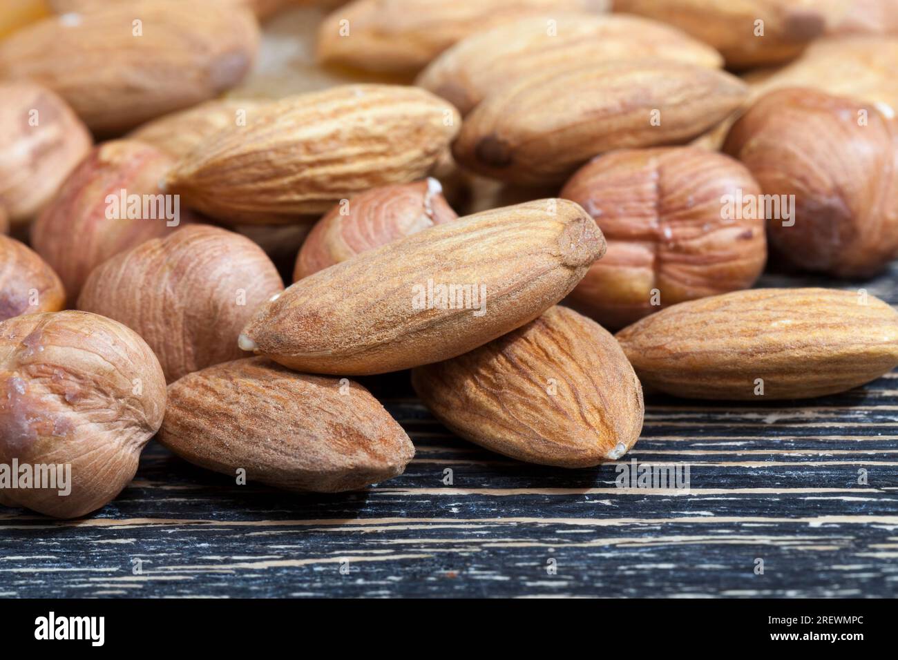 noci crude di qualità pronte da mangiare, mandorle sul tavolo da cucina durante la cottura, mandorle fresche e sbucciate, primo piano, la superficie delle noci non è perfetta Foto Stock