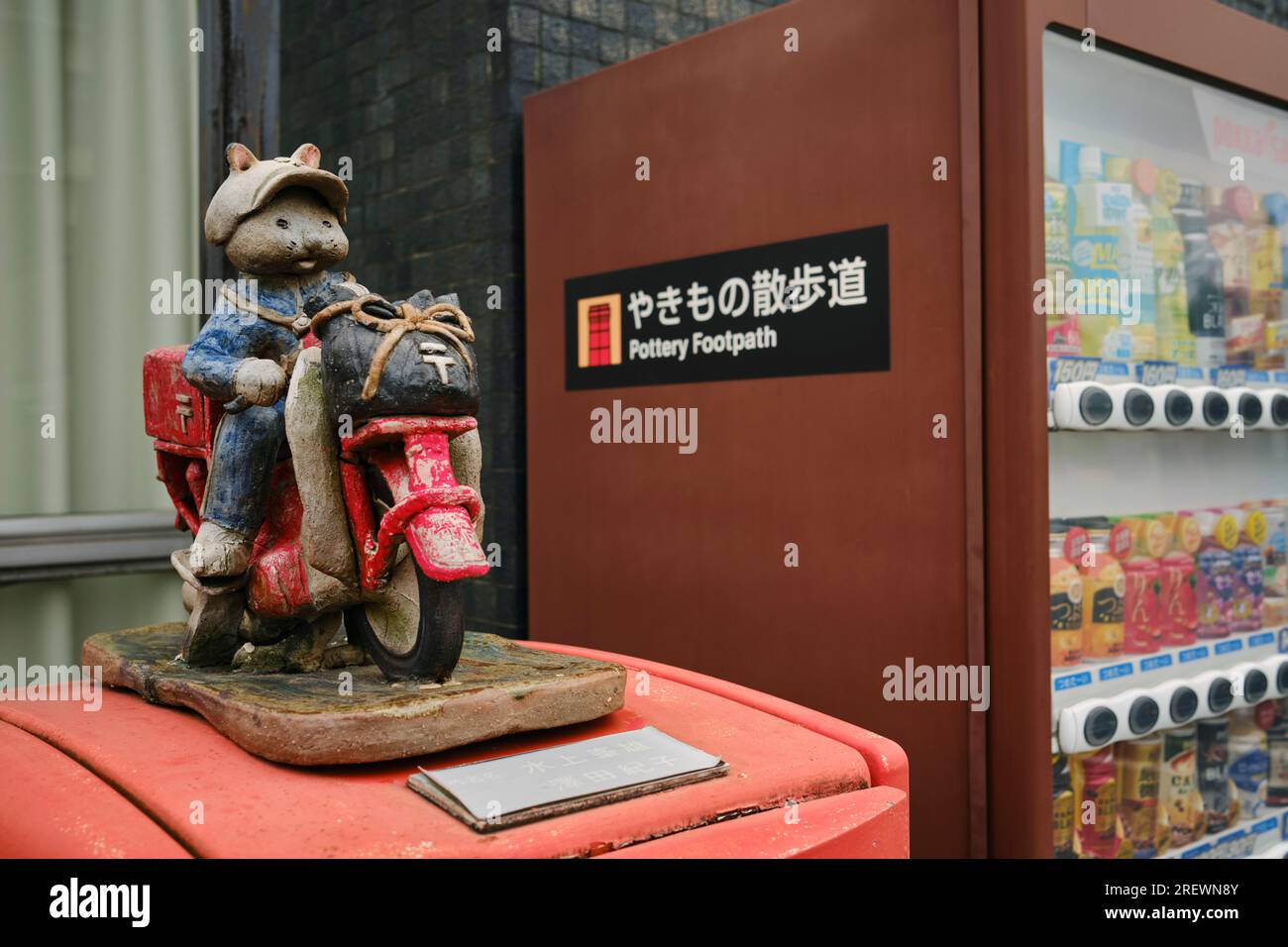 Giugno 2023, Tokoname City. Un postino in ceramica su una decorazione per moto sopra una cassetta postale accanto a un distributore automatico di bevande Foto Stock