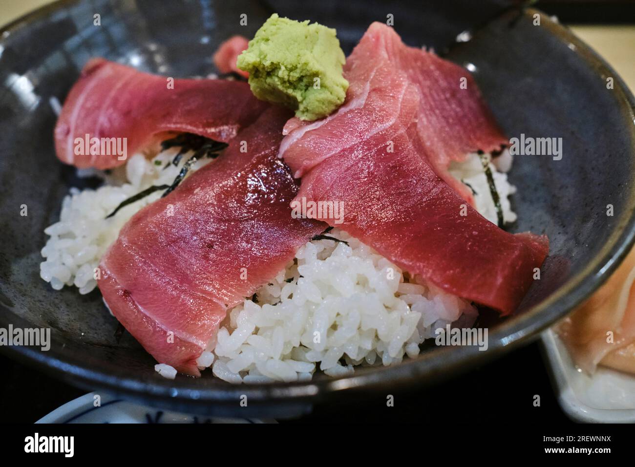 Luglio 2023, Una ciotola di riso al tonno (maguro) con fette di tonno crudo e condimento di wasabi Foto Stock