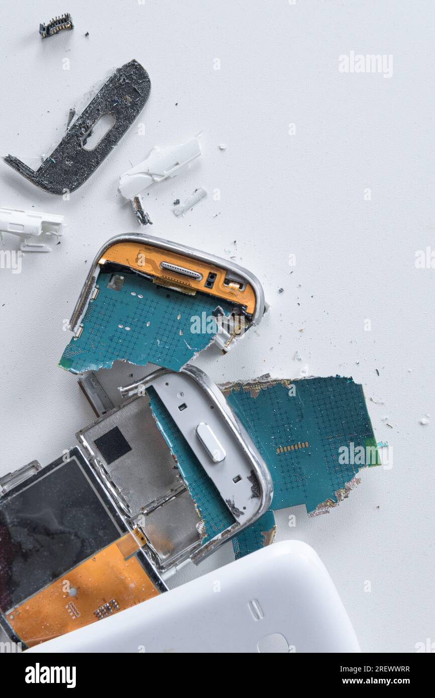 Smartphon rotto sul tavolo bianco. Verticale. L'interno di uno smartphone caduto in una custodia bianca. vista dall'alto ravvicinata Foto Stock