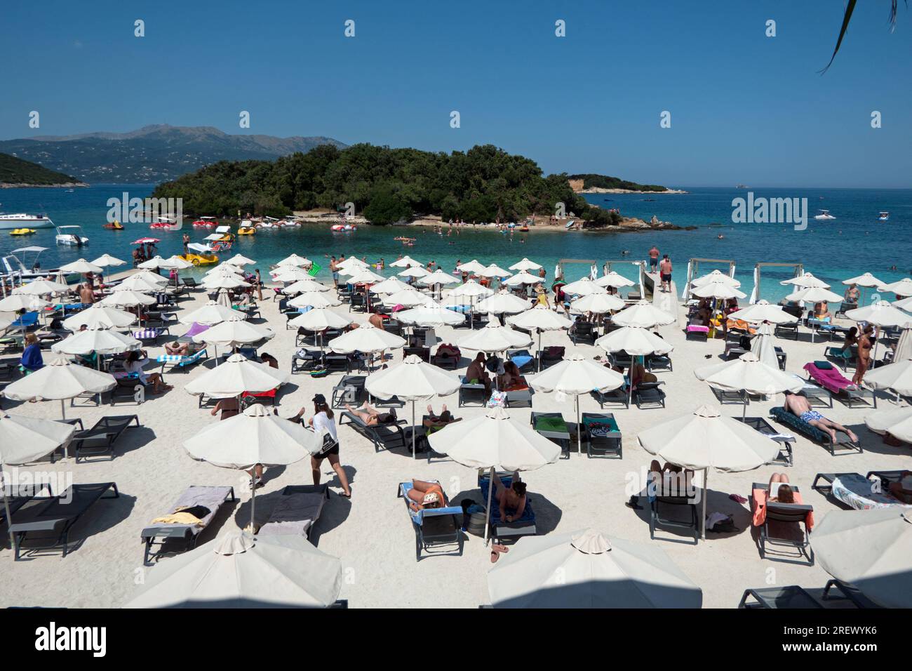 Vista della spiaggia affollata di Ksamil, Albania, con persone che nuotano e si divertono vicino al 3 resort di Ishujt. Turisti che si godono l'estate in una destinazione albanese Foto Stock