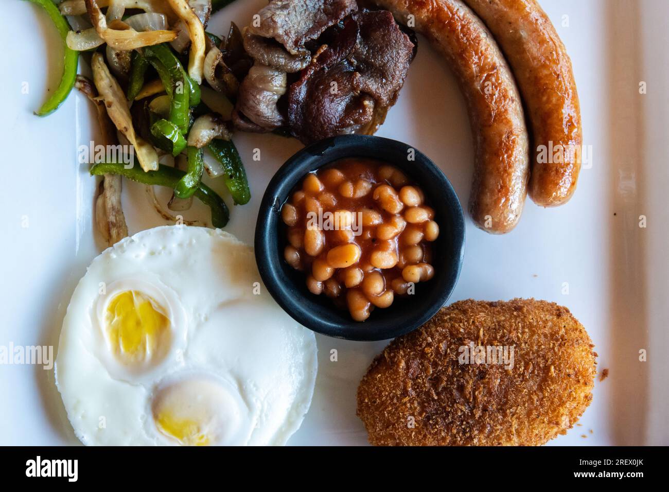 Colazione all'americana con uova, salsicce, pancetta, fagioli, patate con hash Brown e verdure saltate Foto Stock