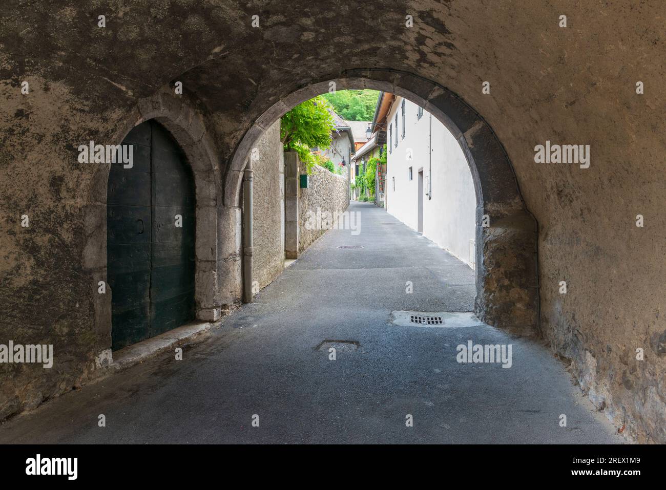 Stradine della città vecchia francese in Provenza. Arco e pareti in pietra, porte d'epoca e fiori sulle finestre Foto Stock