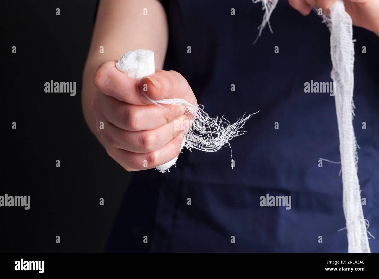 benda bianca medica nelle mani di un medico femminile, un uomo in abbigliamento medico tiene una benda bianca nelle sue mani per trattare urti, lesioni e altro Foto Stock