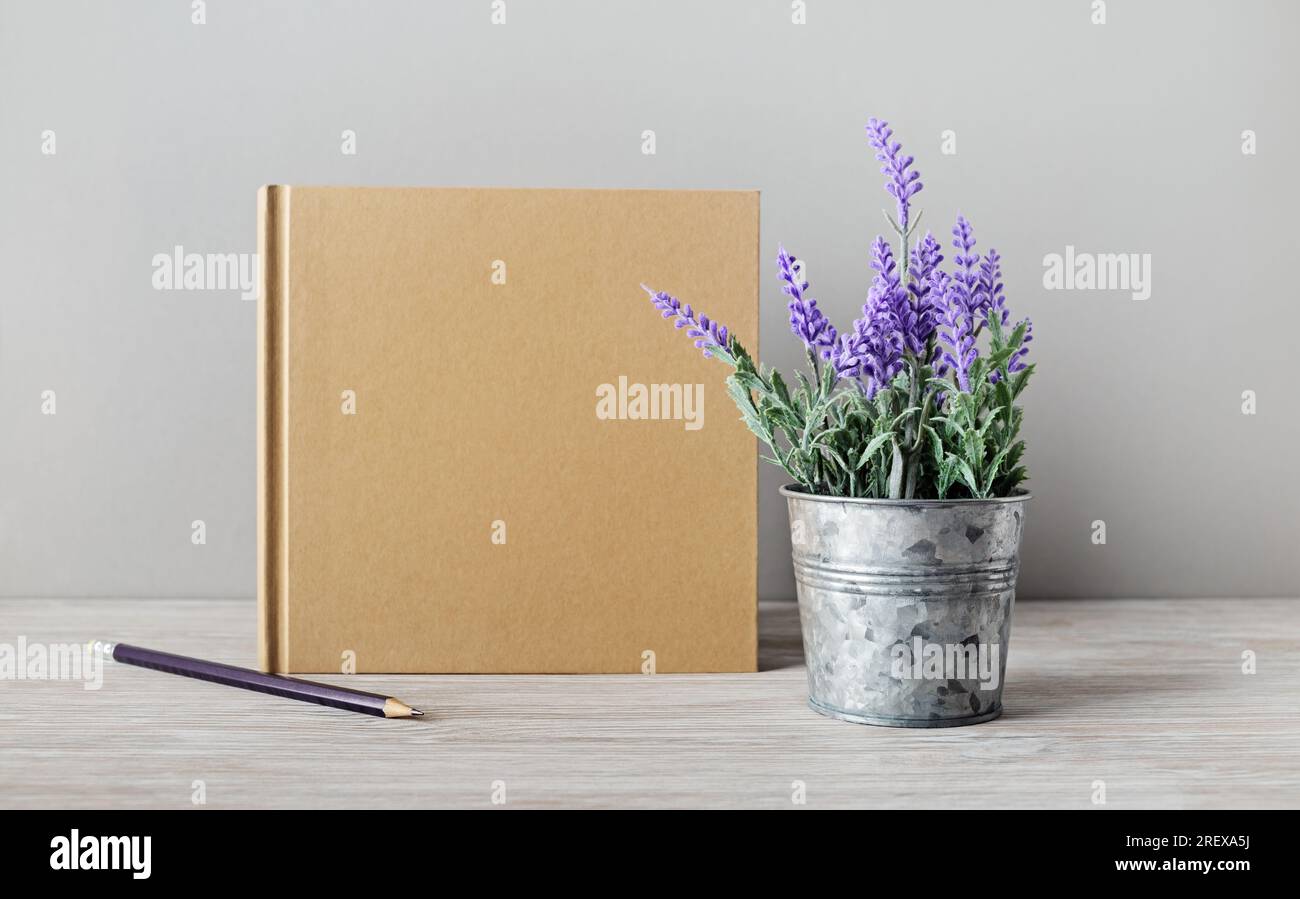 Libro kraft vuoto, matita e lavanda artificiale. Modello per portafogli di grafici. Foto Stock