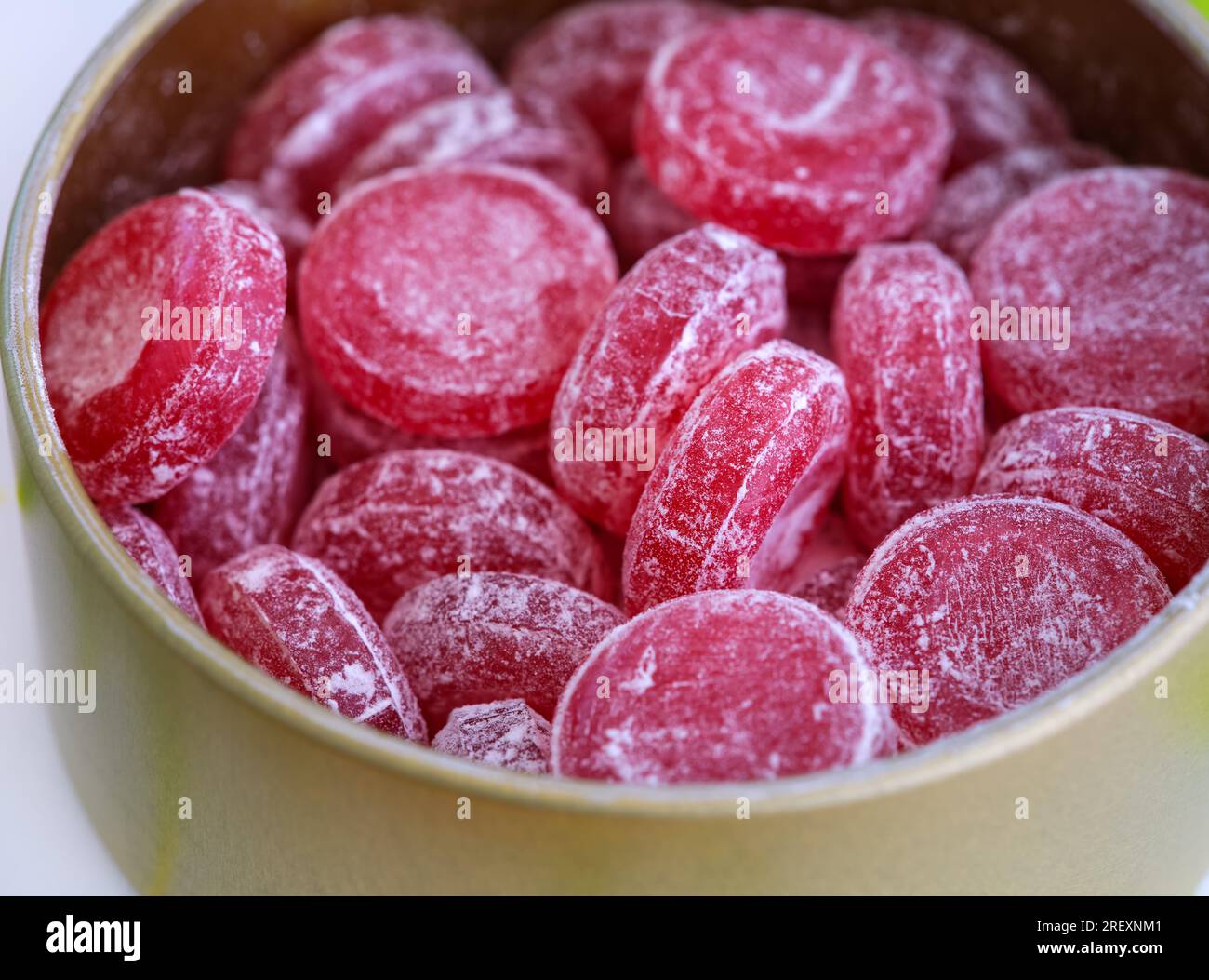 Un primo piano di una scatola di latta aperta piena di caramelle a goccia di ciliegie acide Foto Stock