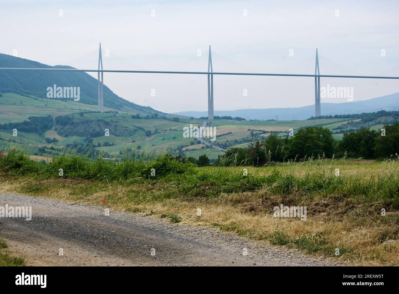 Strada sterrata con vista sul viadotto di Millau in un paesaggio rurale francese. Foto Stock