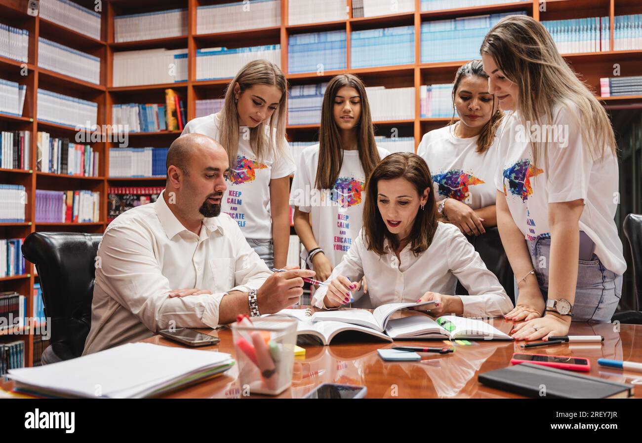 Due professori che mostrano e spiegano ai loro studenti di un progetto mentre si trovano in biblioteca Foto Stock