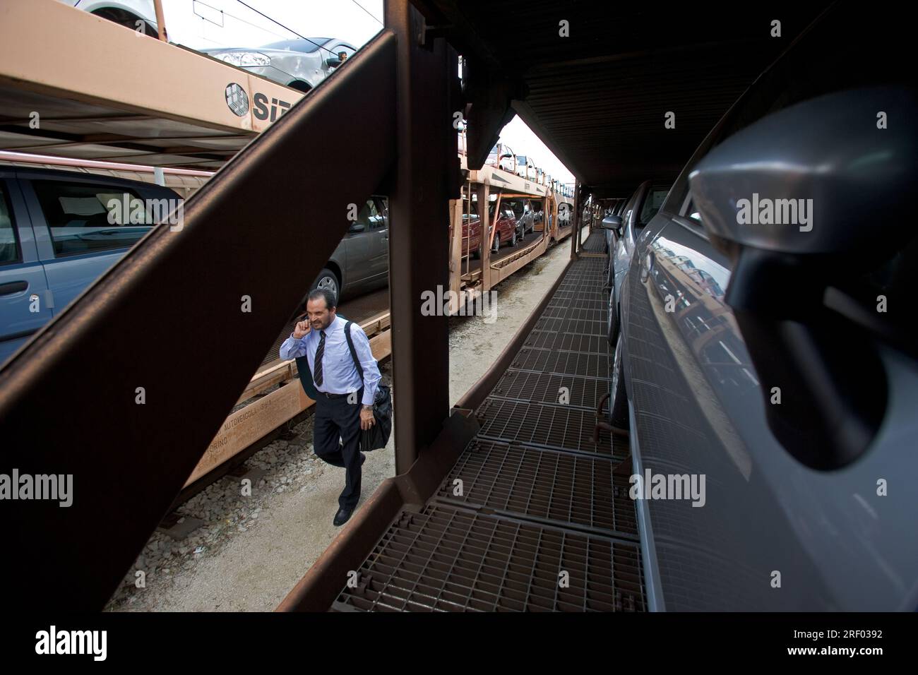 Un macchinista che cammina verso la parte anteriore del suo treno merci che trasporta auto nuove, Trenitalia, il sistema ferroviario nazionale italiano, 2005 Foto Stock
