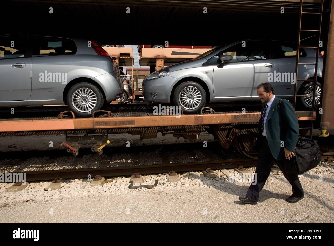 Un macchinista che cammina verso la parte anteriore del suo treno merci che trasporta auto nuove, Trenitalia, il sistema ferroviario nazionale italiano, 2005 Foto Stock