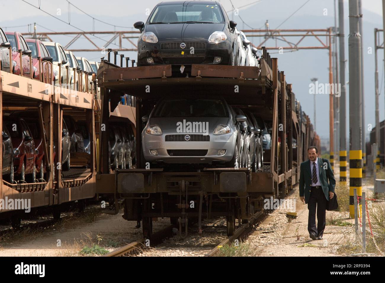 Un macchinista che cammina verso la parte anteriore del suo treno merci che trasporta auto nuove, Trenitalia, il sistema ferroviario nazionale italiano, 2005 Foto Stock