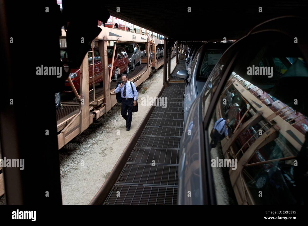 Un macchinista che cammina verso la parte anteriore del suo treno merci che trasporta auto nuove, Trenitalia, il sistema ferroviario nazionale italiano, 2005 Foto Stock