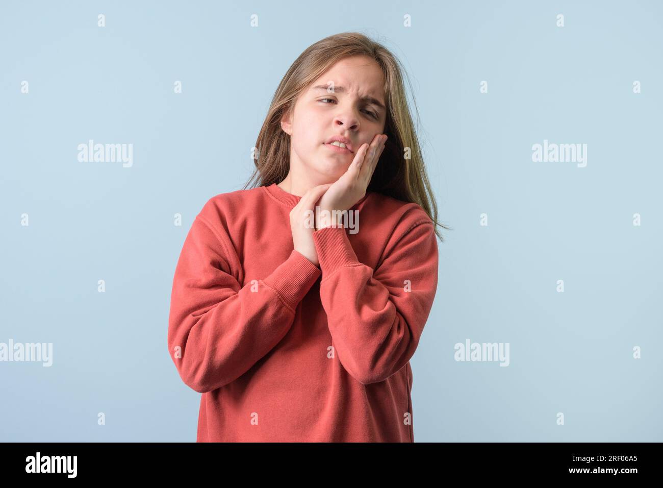 Giovane ragazza su sfondo isolato azzurro chiaro che indossa un maglione rosso che tocca la bocca con la mano con un'espressione dolorosa. Dentista Foto Stock
