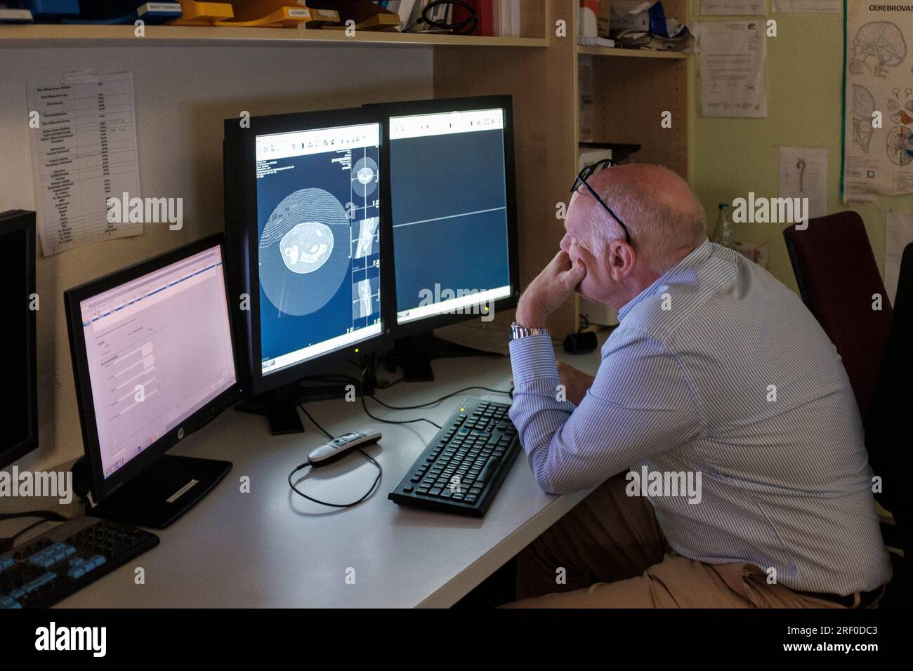 Radiologo che guarda i monitor che visualizzano la scansione RM dell'avambraccio della paziente Foto Stock