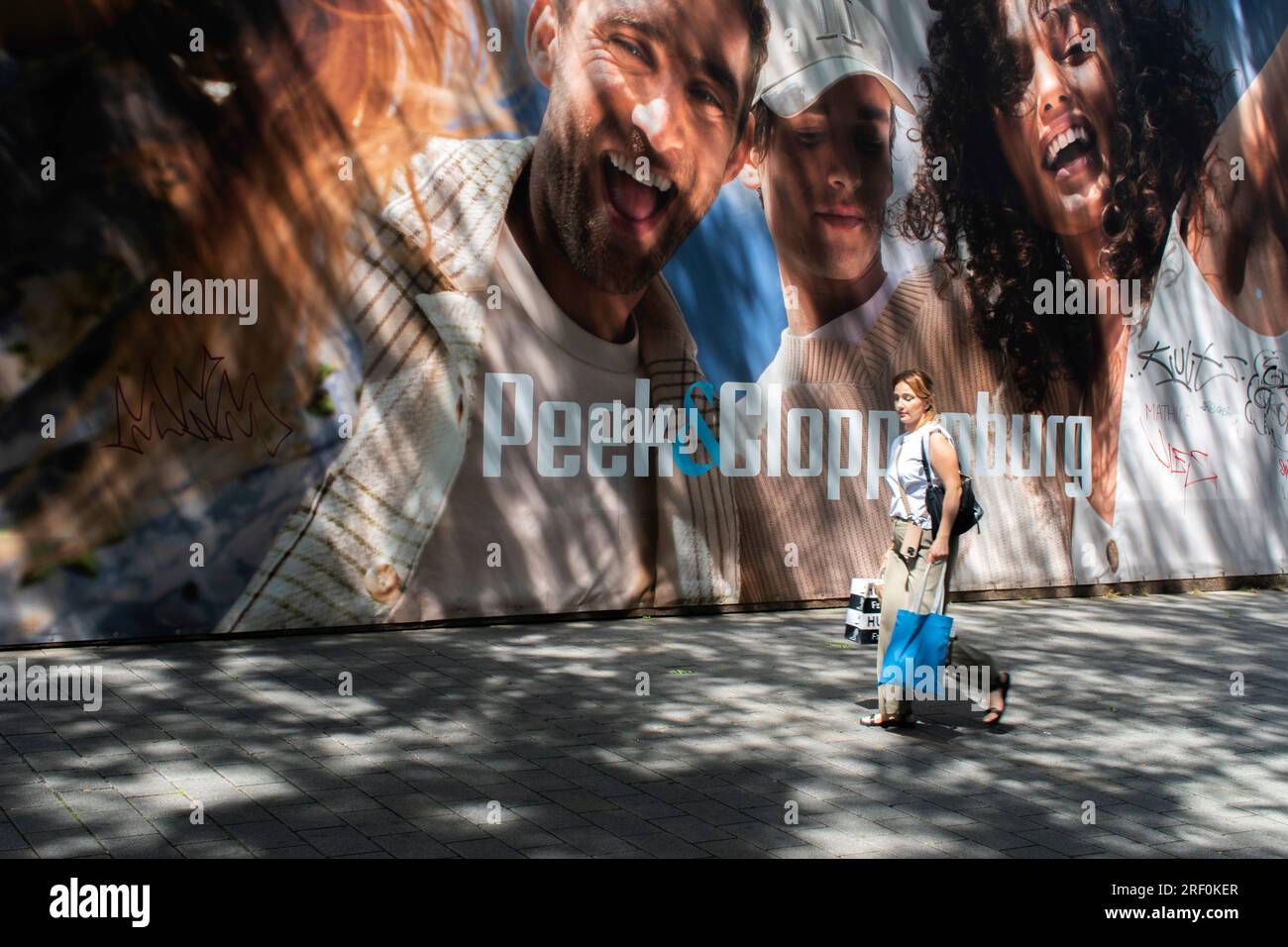 Vienna, Austria. 28 luglio 2023: Un'istantanea della vita cittadina con i pedoni che passano accanto a uno striscione vibrante, con luci e ombre che ballano per strada. Foto Stock