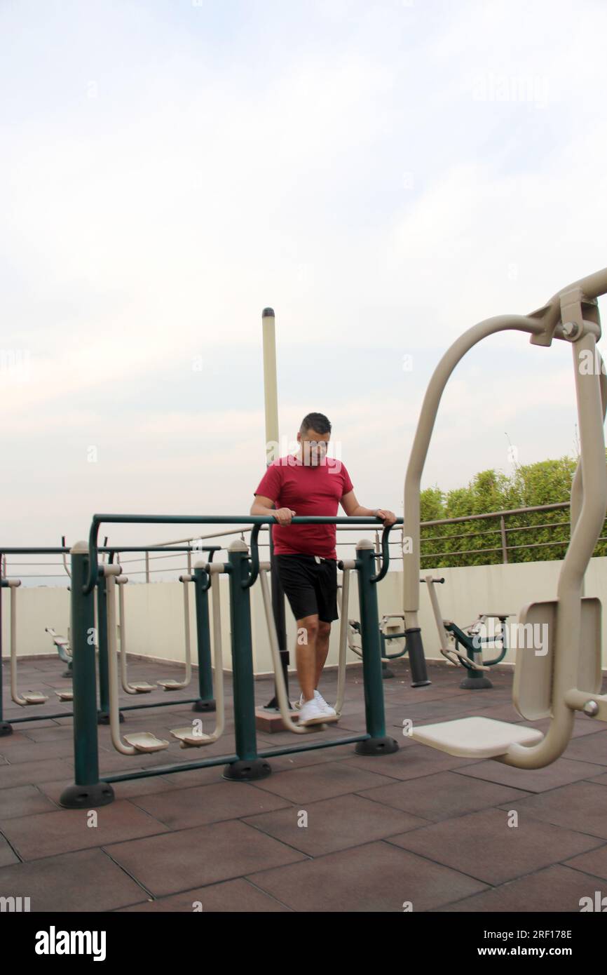 L'uomo latino-americano dai capelli scuri, 40 anni, si esercita sul giardino pensile del suo condominio per prevenire sovrappeso, diabete e ipertensione Foto Stock