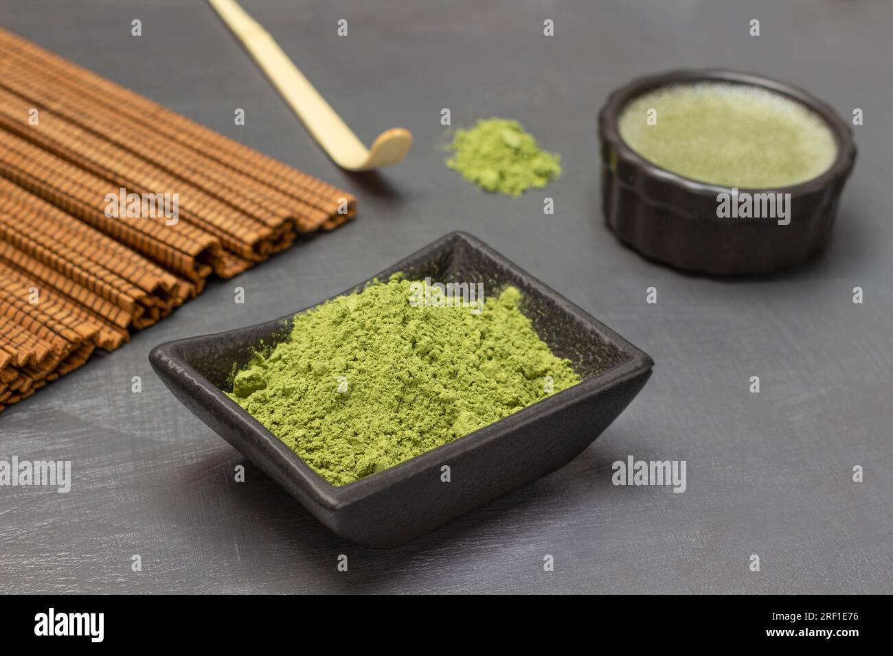 Polvere di tè verde Matcha in una ciotola. Misurino e tè verde. Sfondo grigio. Foto Stock