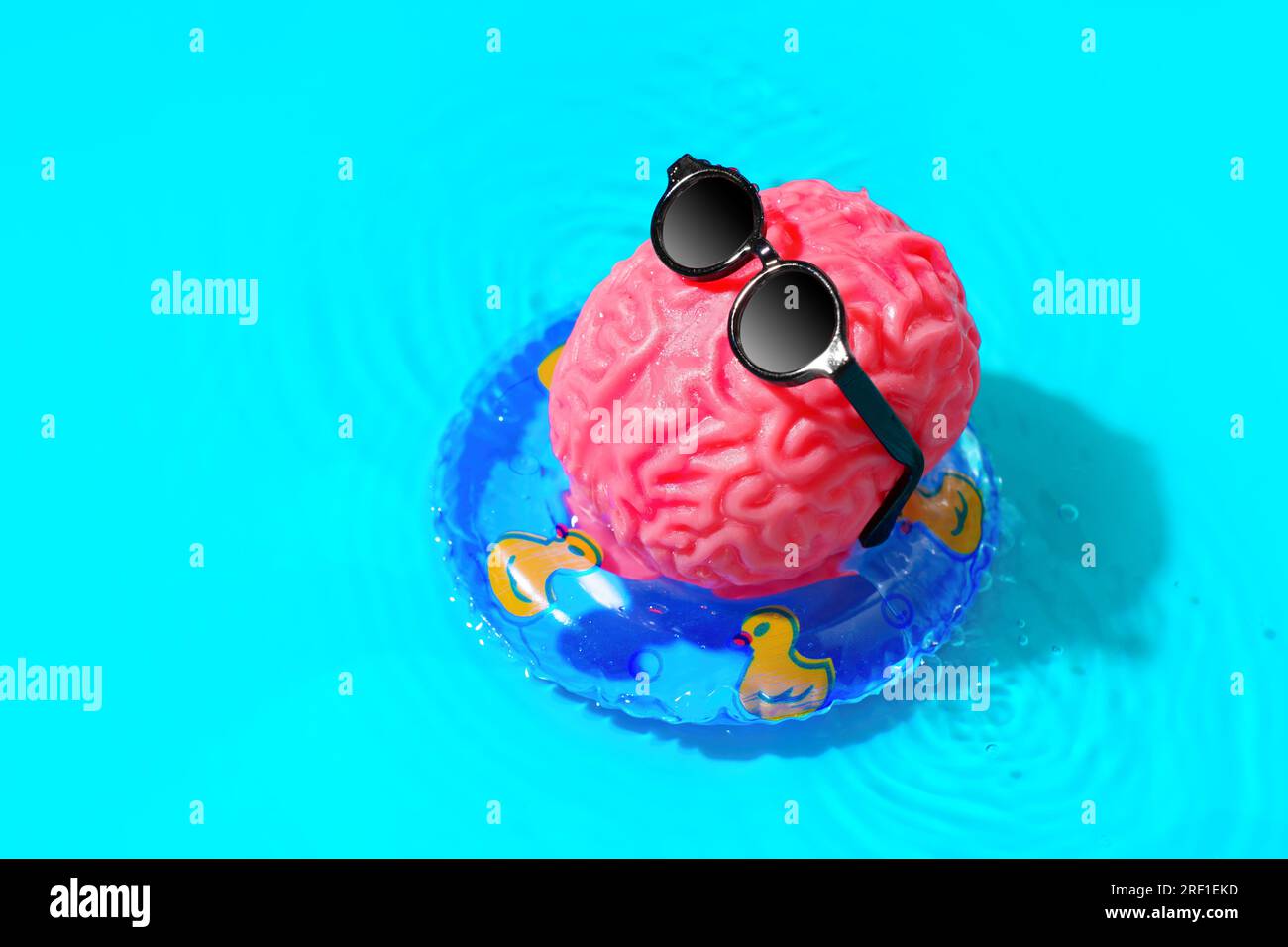 Il cervello umano, adornato con eleganti occhiali da sole, si vizierà con una rilassante sessione di prendere il sole mentre galleggia aggraziatamente in un anello della piscina. Rejuv mentale Foto Stock