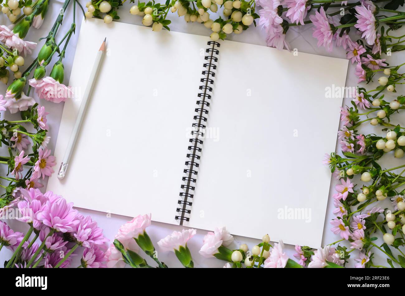 Quaderno bianco vuoto con fiori rosa su sfondo bianco. Foto Stock