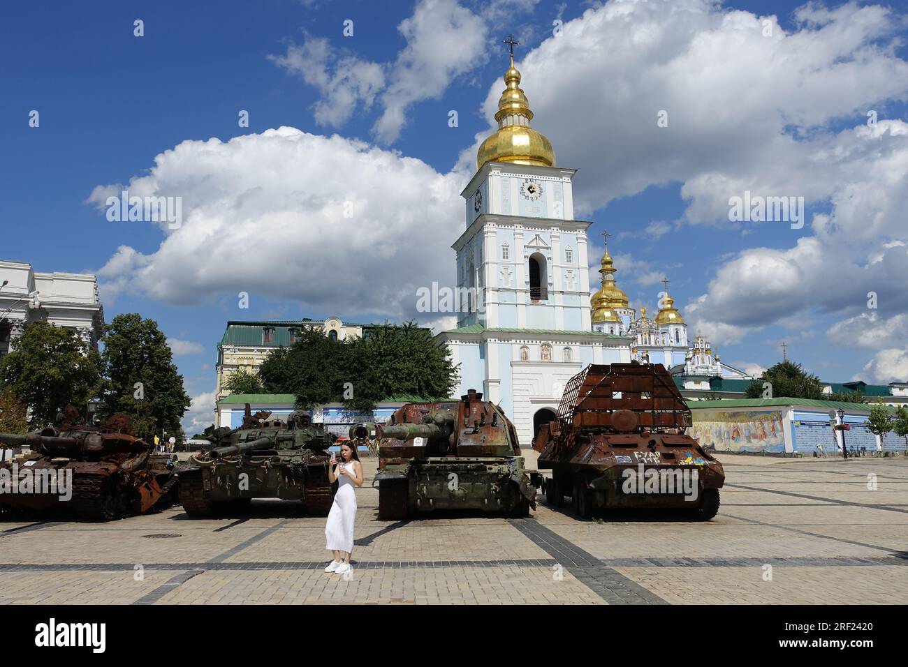 Una ragazza sta facendo un selfie davanti ai veicoli corazzati dell'esercito russo distrutti esposti in una piazza nel centro di Kiev, in Ucraina Foto Stock