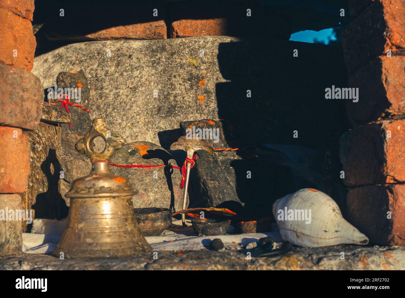 Luogo di preghiera indù d'epoca a Uttarakhand, India, con vecchia campana, shanka e statua della divinità. Foto Stock