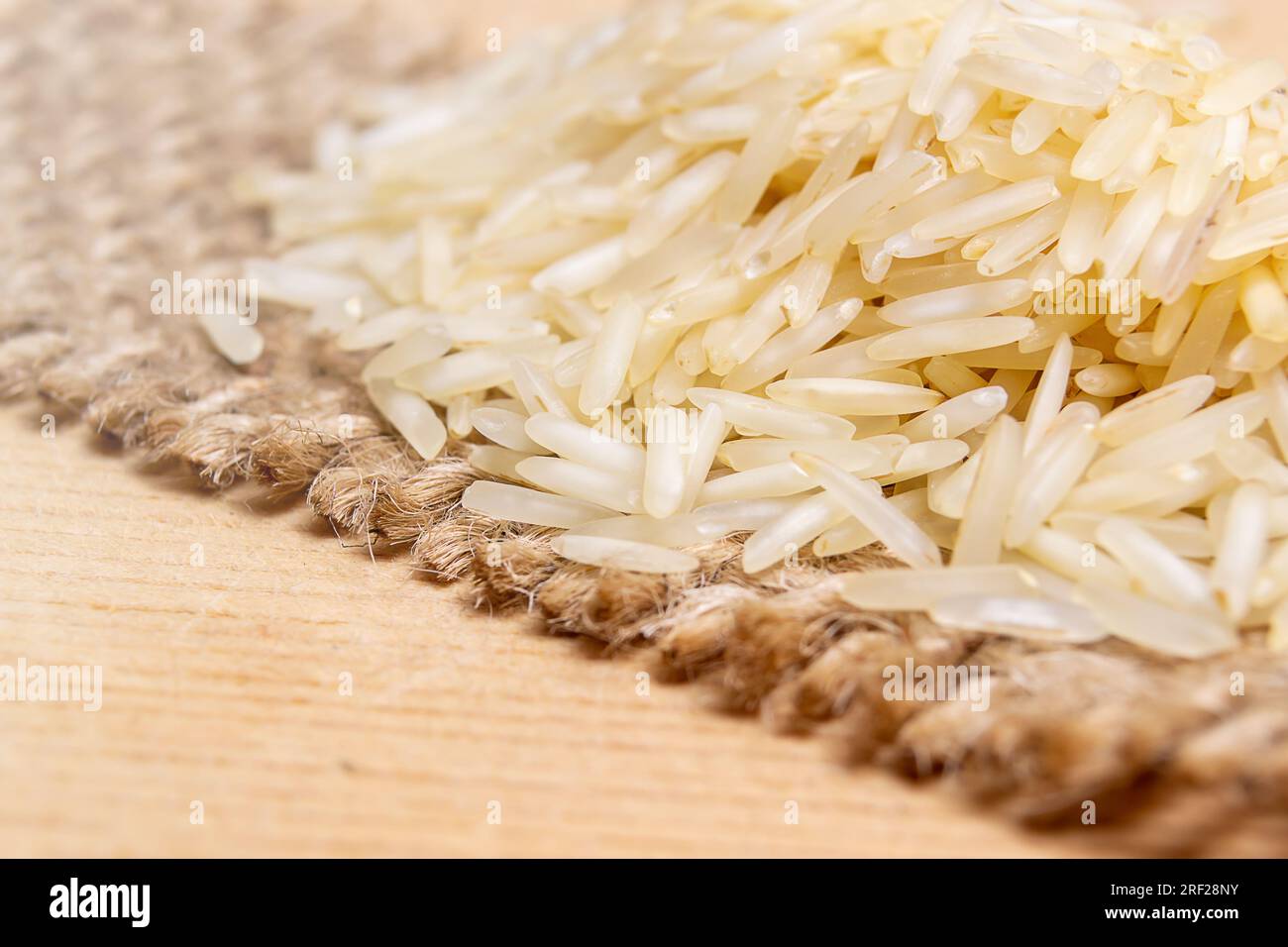 Riso sopra un tessuto di iuta su una superficie di legno Foto Stock