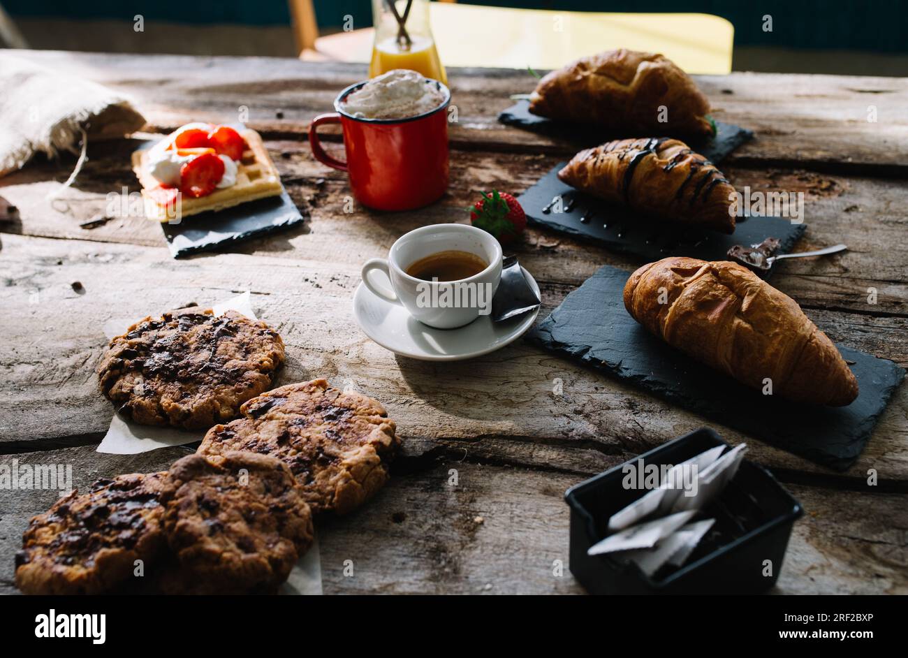 Croissant, caffè, torta, panna e fragole crude su un tavolo di legno. Foto Stock