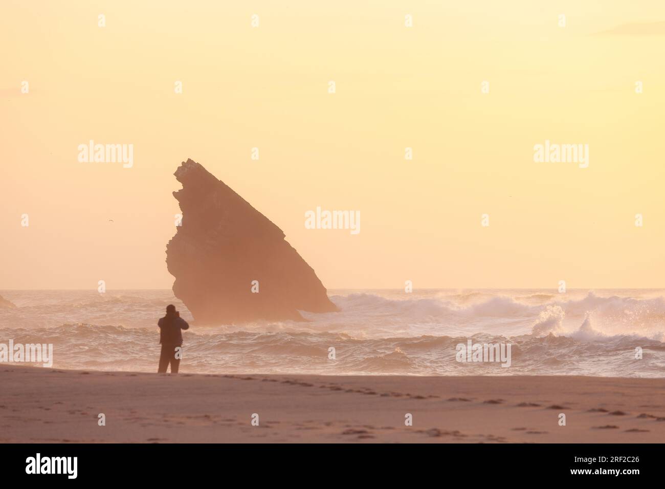 Tramonto sulla costa rocciosa della spiaggia di Adraga con silhouette maschile Foto Stock