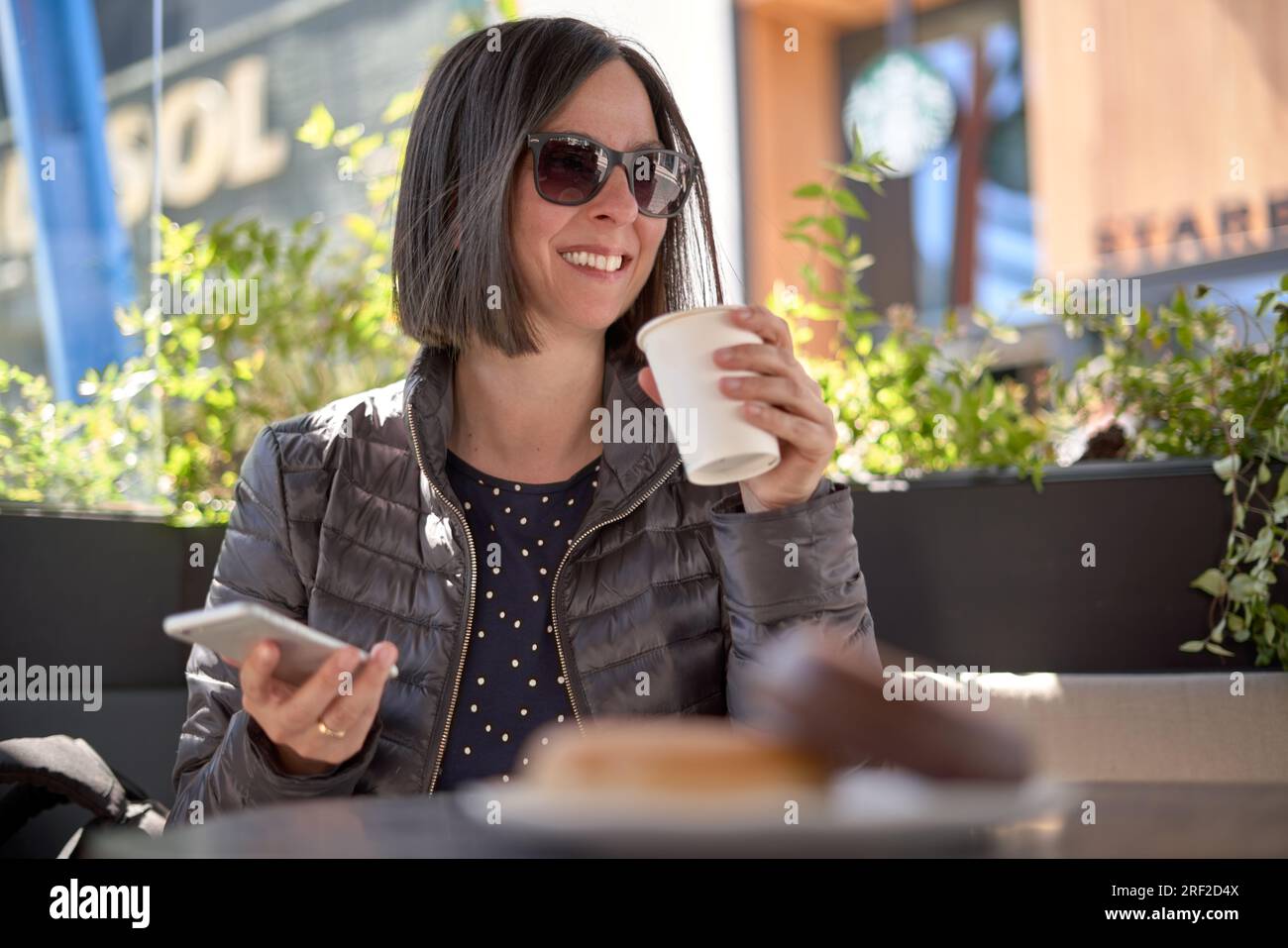 Donna con la colazione e con il suo telefono cellulare Foto Stock