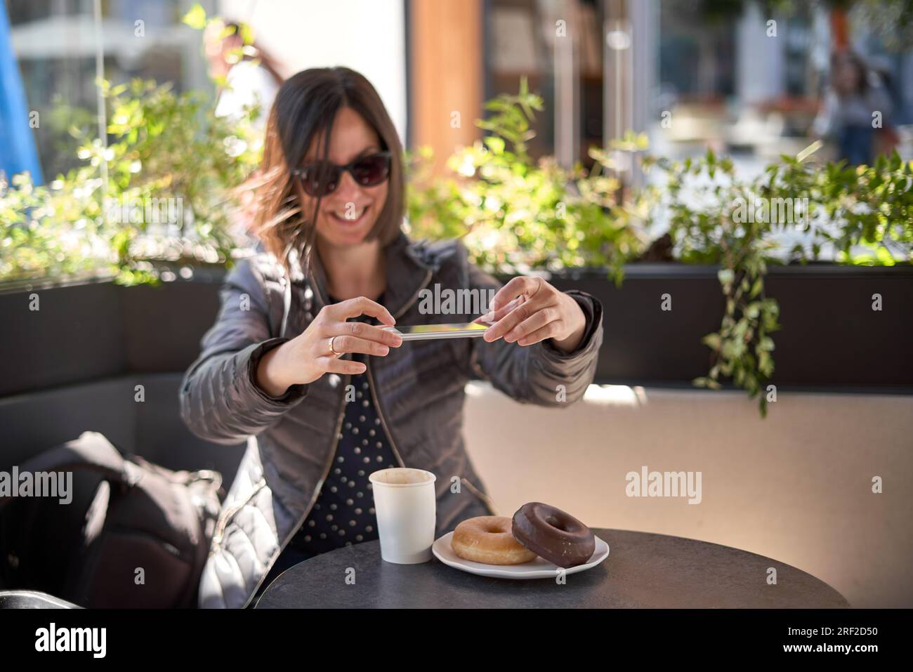 Donna con la colazione e con il suo telefono cellulare Foto Stock