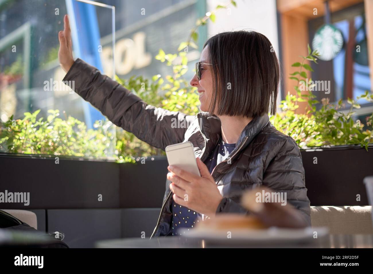 Donna con la colazione e con il suo telefono cellulare Foto Stock