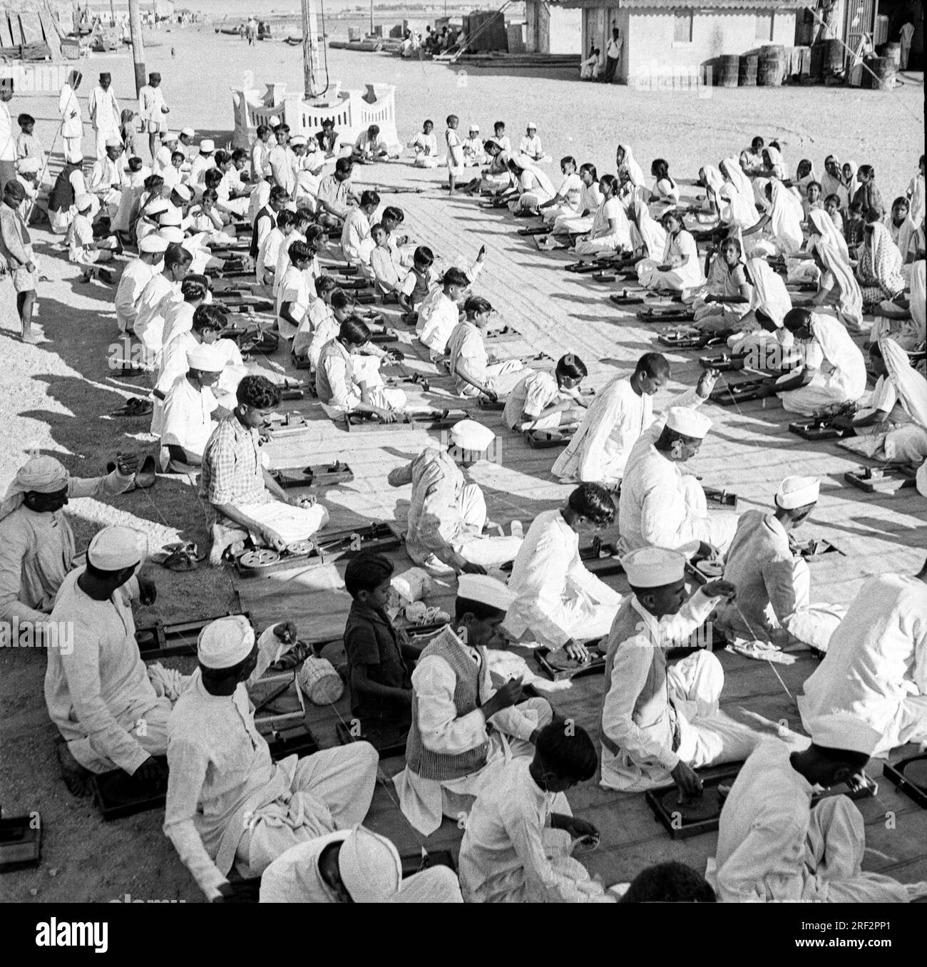 Vecchia immagine vintage in bianco e nero degli anni '1900 degli indiani che imparano a girare la ruota a filato usano l'India 1940s Foto Stock