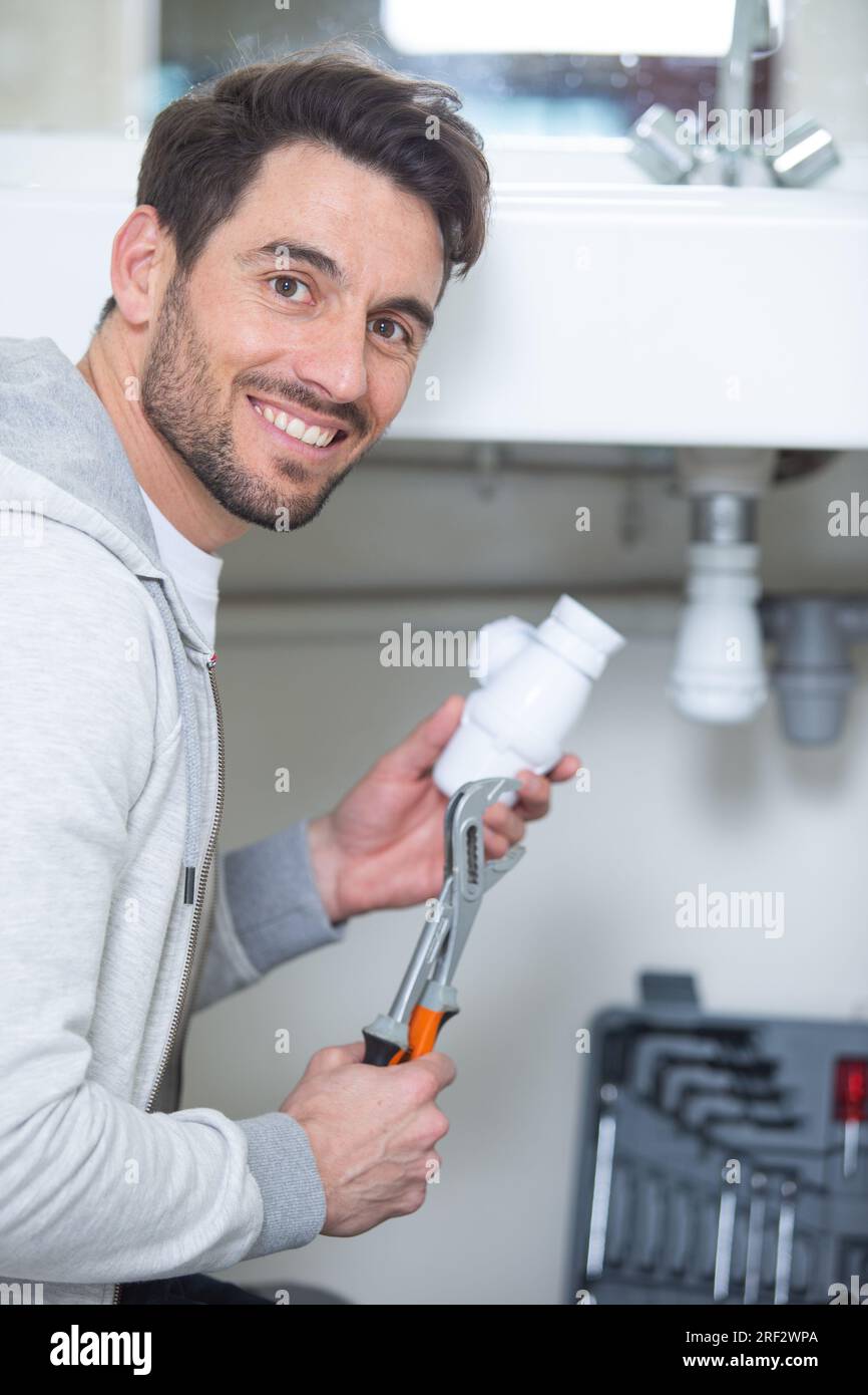 bell'uomo che si fissa sotto il lavandino in cucina Foto Stock