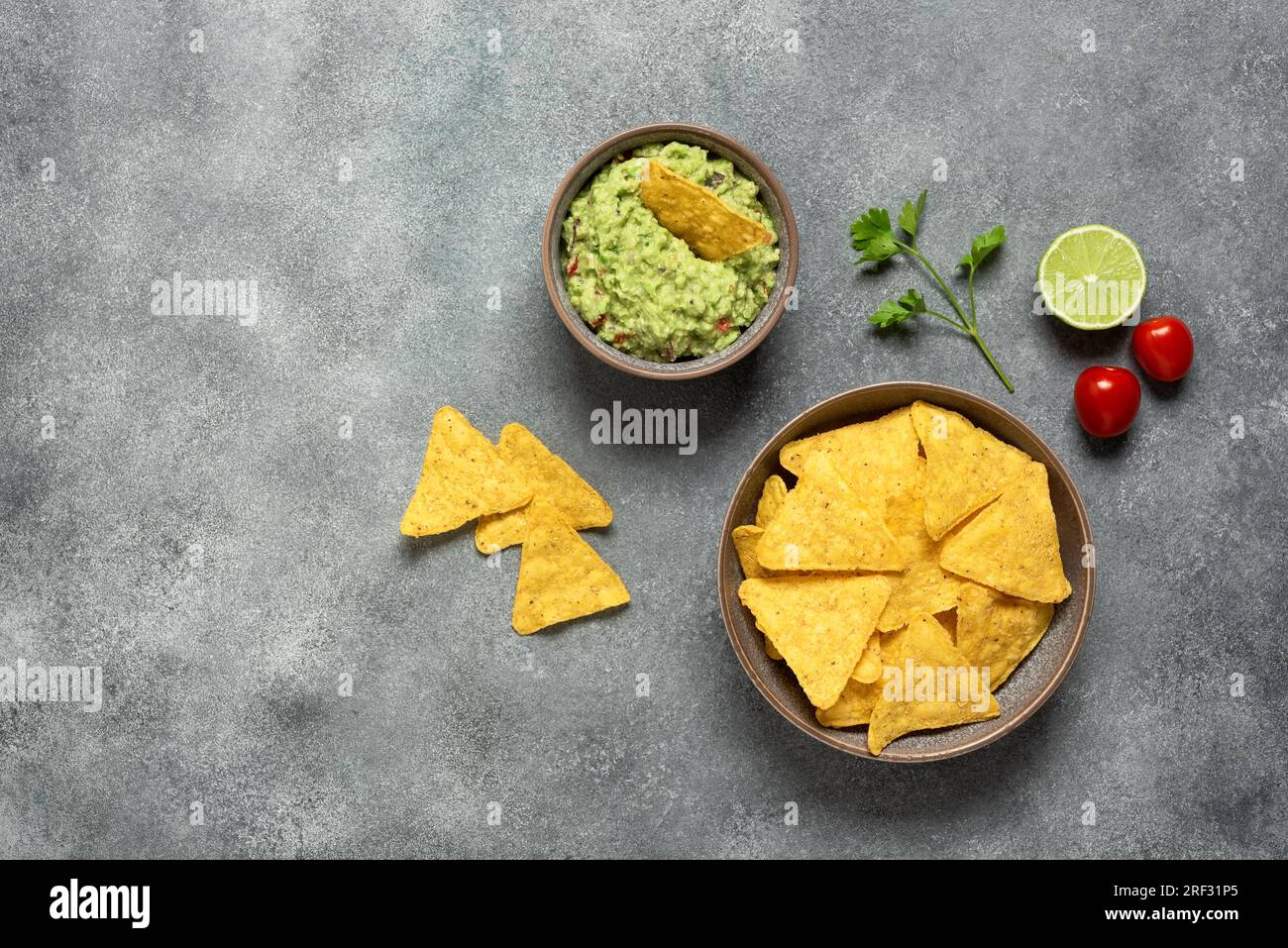 Guacamole con nachos su sfondo grigio. Cibo messicano. Vista dall'alto, base piatta, spazio di copia. Foto Stock