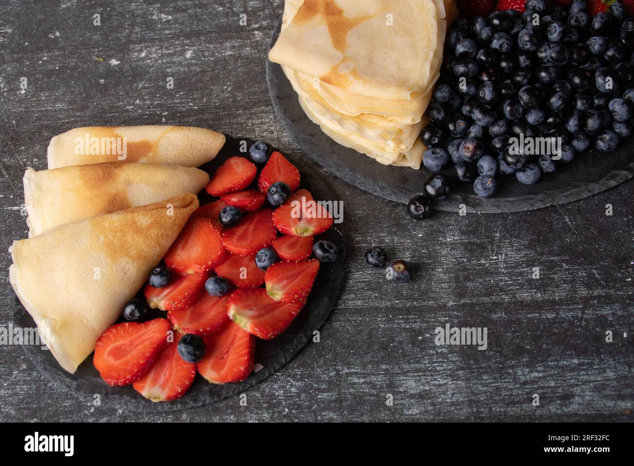scatta foto di fragole mature e succose e mirtilli su un piatto con pancake fatti in casa Foto Stock