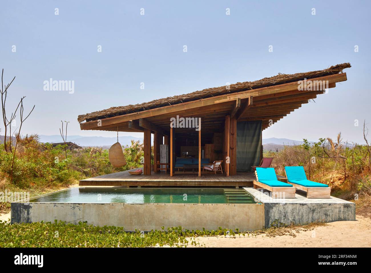 Vista frontale con villa sulla spiaggia con piscina e lettini. Punta Pajaros, Oaxaca, Messico. Architetto: Alberto Kalach, 2019. Foto Stock