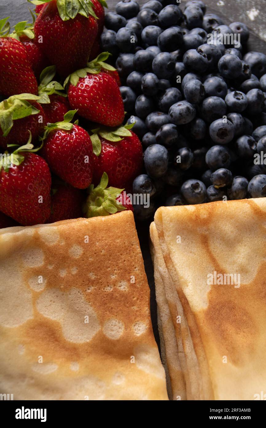 foto di pancake sottili fritti con fragole succose e fresche mature e mirtilli da vicino Foto Stock