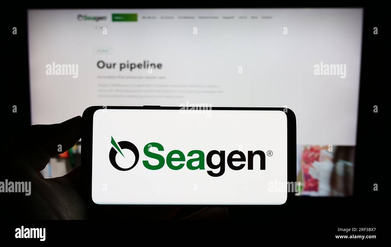 Persona in possesso di un cellulare con il logo della società statunitense di biotecnologia Seagen Inc. Sullo schermo di fronte alla pagina Web aziendale. Concentrarsi sul display del telefono. Foto Stock
