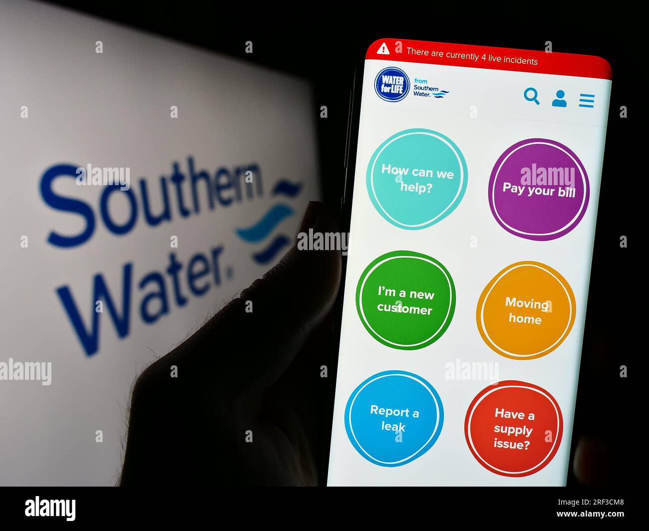 Persona che possiede uno smartphone con il sito Web della società britannica Southern Water Services Limited sullo schermo con logo. Concentrarsi sul centro del display del telefono. Foto Stock